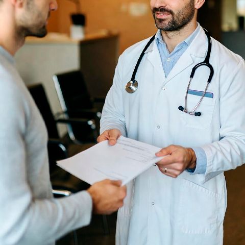 Врач в белом халате обсуждает медицинские документы с пациентом