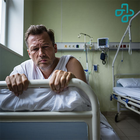 Мужчина в больничной палате лежит на кровати с ломкой